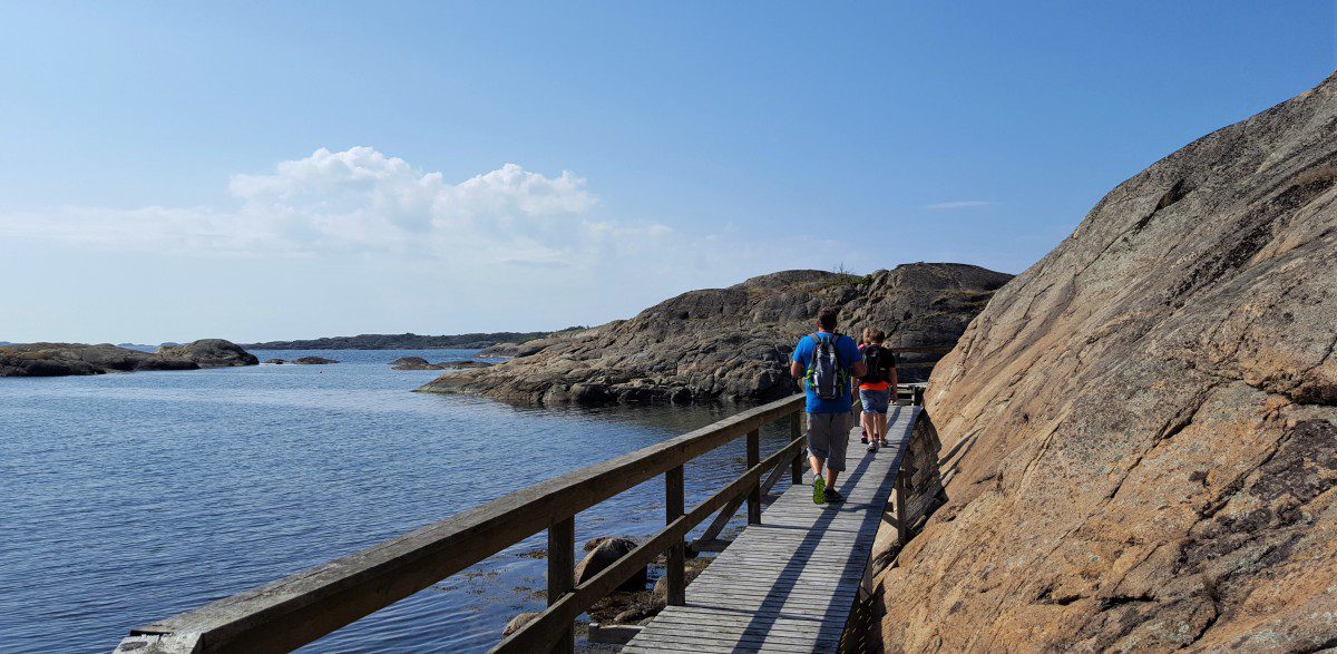 Kyststien med turgåere på tregangbro langs fjorden